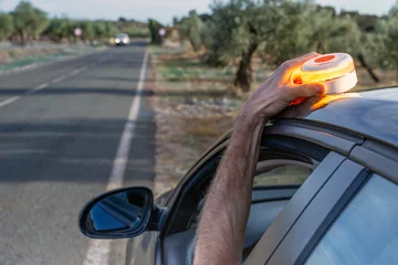 Fototapete Leuchtturm Driver signaling with V16 emergency warning beacon on car roof by roadside in Spain.  © Rafa Jodar