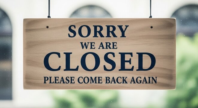 A wooden sign saying sorry we are closed hanging on a glass door