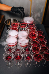 Photo of multiple glasses of red alcoholic cocktail with smoky steam on a table in a restaurant bar.
