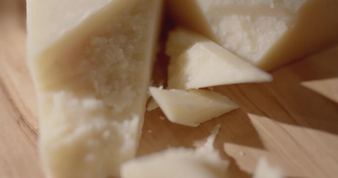 Sliding closeup over a slab of parmesan cheese on a cutting board. Delicious food close up background.