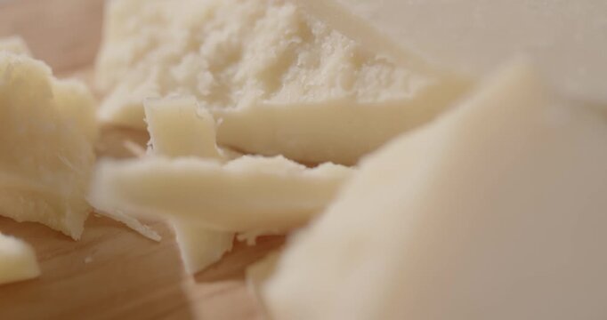 Sliding closeup over a slab of parmesan cheese on a cutting board. Delicious food close up background.