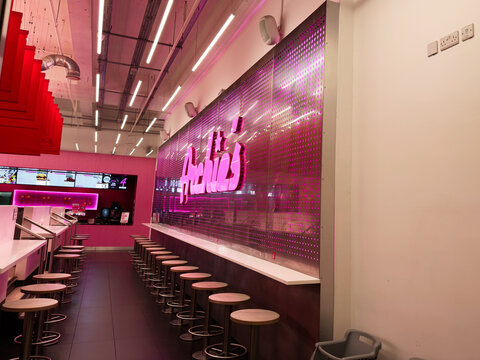 Vibrant pink retro Archie's cafe interior with long counter stools and neon signage