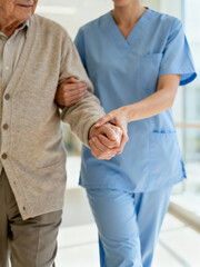 Fototapeta premium A woman in a blue uniform is helping an elderly man