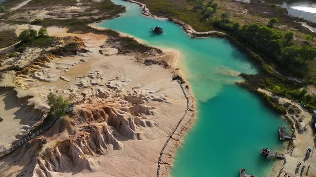 Aerial view of Bintan Blue Lake with striking turquoise water eroded sandy terrain and a winding track creating an otherworldly landscape of nature and industry