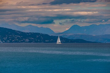 White sailboat on the Ionian Sea after sunset near the island of Corfu