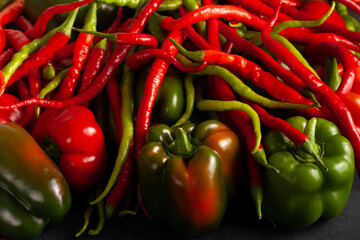 Assortment of fresh red and green bell peppers with spicy chili peppers on a dark background. Vibrant, organic vegetables perfect for cooking, recipes, and healthy food concepts.