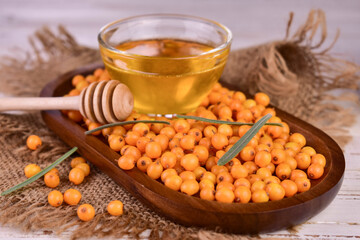 Fresh sea buckthorn berries with honey on a wooden tray.

