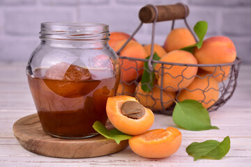 Apricot jam in a jar and fresh apricots in a basket.
