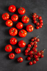 Fresh ripe tomatoes and cherry tomatoes on dark surface. Concept of clean eating, organic vegetables, vegetarian diet, and healthy lifestyle.