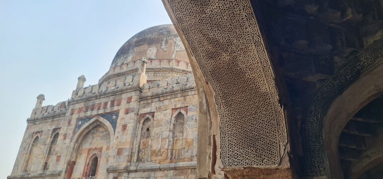 Perspective view of an ancient heritage monument in Lodhi Gardens with grey stone masonry and classic Islamic arches.