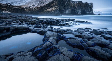 Dramatic coastal landscape with dark basalt rock formations and misty ocean waves