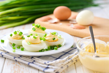 Healthy breakfast concept, boiled chicken eggs with  mayonnaise  and freshly cut chives on a wooden table.