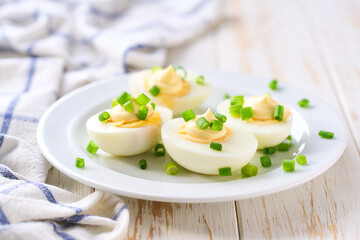 Boiled chicken eggs with  mayonnaise and cut chives on a light kitchen table, selective focus.