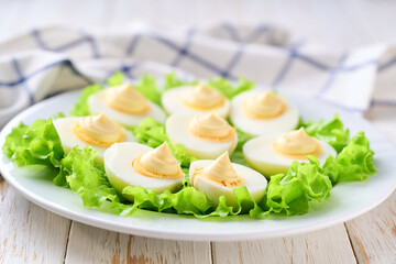 light snack of  hard boiled chicken eggs and mayonnaise on a white table.