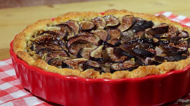 Smooth left to right video shot of freshly baked rustic homemade pear and fig pie on a wooden table