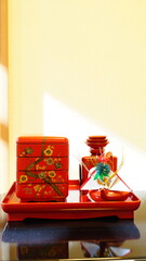 斜めに光が差し込む和室に置かれた、正月の屠蘇器とおせち料理の重箱(縦構図)(4534)