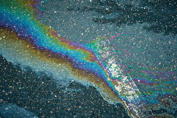 Oil slick on wet asphalt creating a vibrant, abstract rainbow pattern