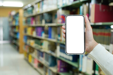 Hand holding smart phone with blank screen mock up on blur library room with bookshelves background. education, eBook, digital library, electronic library application, media store concept.