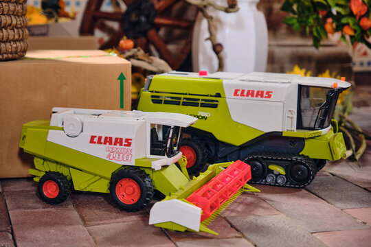 Two CLAAS toy combine harvesters, Lexion 480 and Lexion 780 models, displayed indoors at a fair, symbolizing modern agricultural machinery, reusing and rural heritage