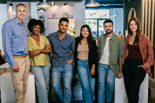 Diverse group of successful business team standing together at modern office. Teamwork, leadership and collaboration concept