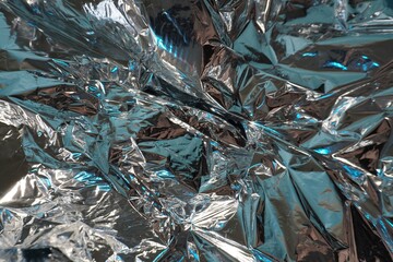Crumpled aluminum foil with cold blue highlights. Shiny metallic texture, reflections, folds, abstract background, close-up.