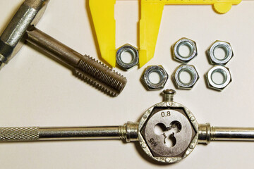 Industrial composition. Tap, nuts, and calipers on a white background.
