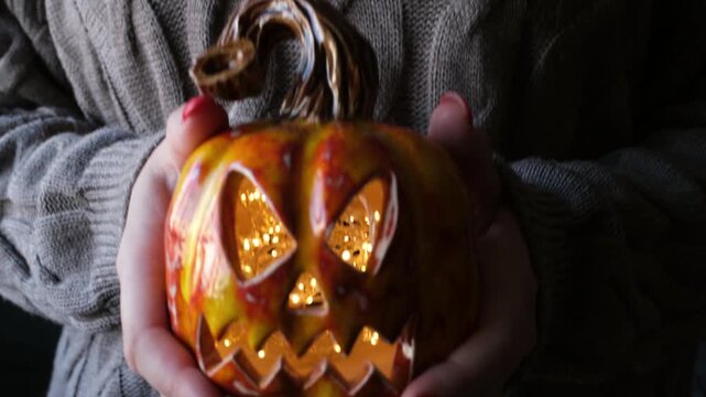 Spooky pumpkin glow: person holding halloween lantern in cozy sweater