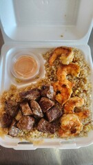 Assorted Grilled Meats, Shrimp, Vegetables, and Rice in Takeout Container with Sweet Sauce
