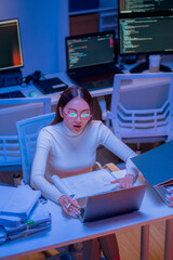 Asian female smart programmer works late night office coding deep learning AI models, training...