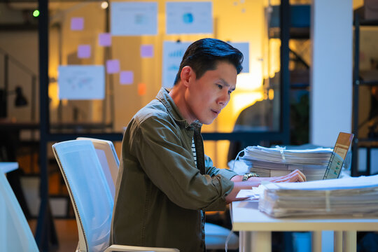 Asian programmer works late night office coding deep learning AI models, training neural networks with intense concentration and focus, dedicating overtime hours alone to machine learning development 