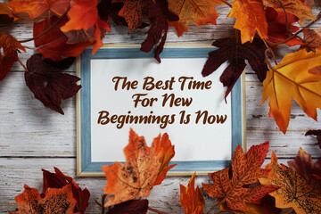 The Best Time For New Beginnings Is Now text with maple leaf decoration on wooden background
