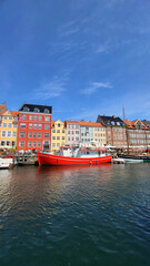 07 August, 2024, Copenhagen city center, Denmark Summer day scenic canal with boats and tourists, cyclists riding along colorful buildings and waterfront, vibrant urban atmosphere in European capital