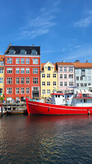 07 August, 2024, Copenhagen city center, Denmark Summer day scenic canal with boats and tourists, cyclists riding along colorful buildings and waterfront, vibrant urban atmosphere in European capital