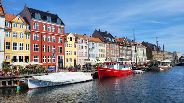 07 August, 2024, Copenhagen city center, Denmark Summer day scenic canal with boats and tourists, cyclists riding along colorful buildings and waterfront, vibrant urban atmosphere in European capital