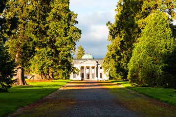 Sunlit Emo Court House framed by tall trees and vibrant green lawns in County Laois, Ireland