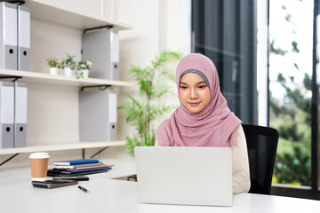 Muslim business executive woman in hijab  using laptop in office. Smiling businesswoman company...