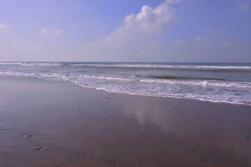 Expansive seascape of Cox's Bazar beach on the Bay of Bengal in Bangladesh, with a vast blue sky and gentle waves.
