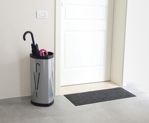 Umbrella stand organizing entryway in condominium hallway