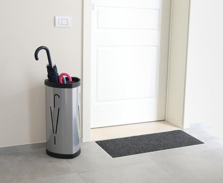 Umbrella stand organizing entryway in condominium hallway