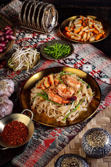 Exquisite Pad Thai Dish with Shrimp and Garnishes on a Golden Plate.