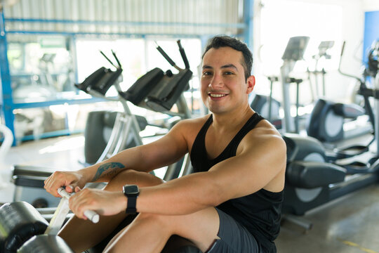 Hispanic man smiling while exercising on rowing machine