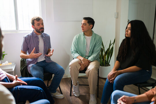 Sad man speaking in group therapy session