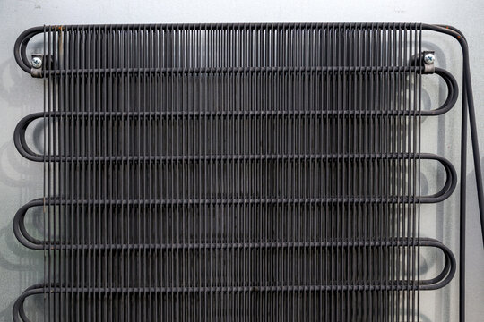 Metal grid condenser coils on refrigerator back panel, showing industrial structure and functional cooling system detail