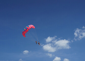 Parachute flights, two people flying on a parachute, against the background of the blue sky.