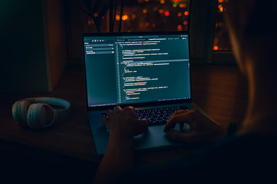 Programmer's hands are coding on a laptop in the dark with a view of the lights of the night city. The concept of a developer or hacker. Saint Petersburg, Russia - 23 Oct 2025 - Powered by Adobe