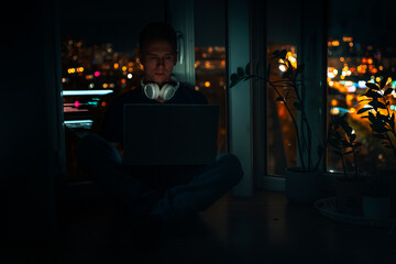 Obraz premium A young male developer is programming a code script late at night with beautiful city lights at night.