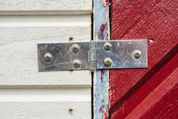 Close up of metal hinge on wooden panels.