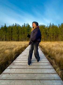 Joyful Young Woman Dancing on Boardwalk in Beautiful Autumn Nature