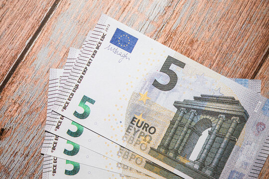 Close up of five euro banknotes on wooden surface.