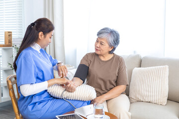 Obraz premium Asian caregiver nurse assisting elderly senior woman at home during medical checkup, measuring blood pressure and providing healthcare support, doctor visit and homecare service concept